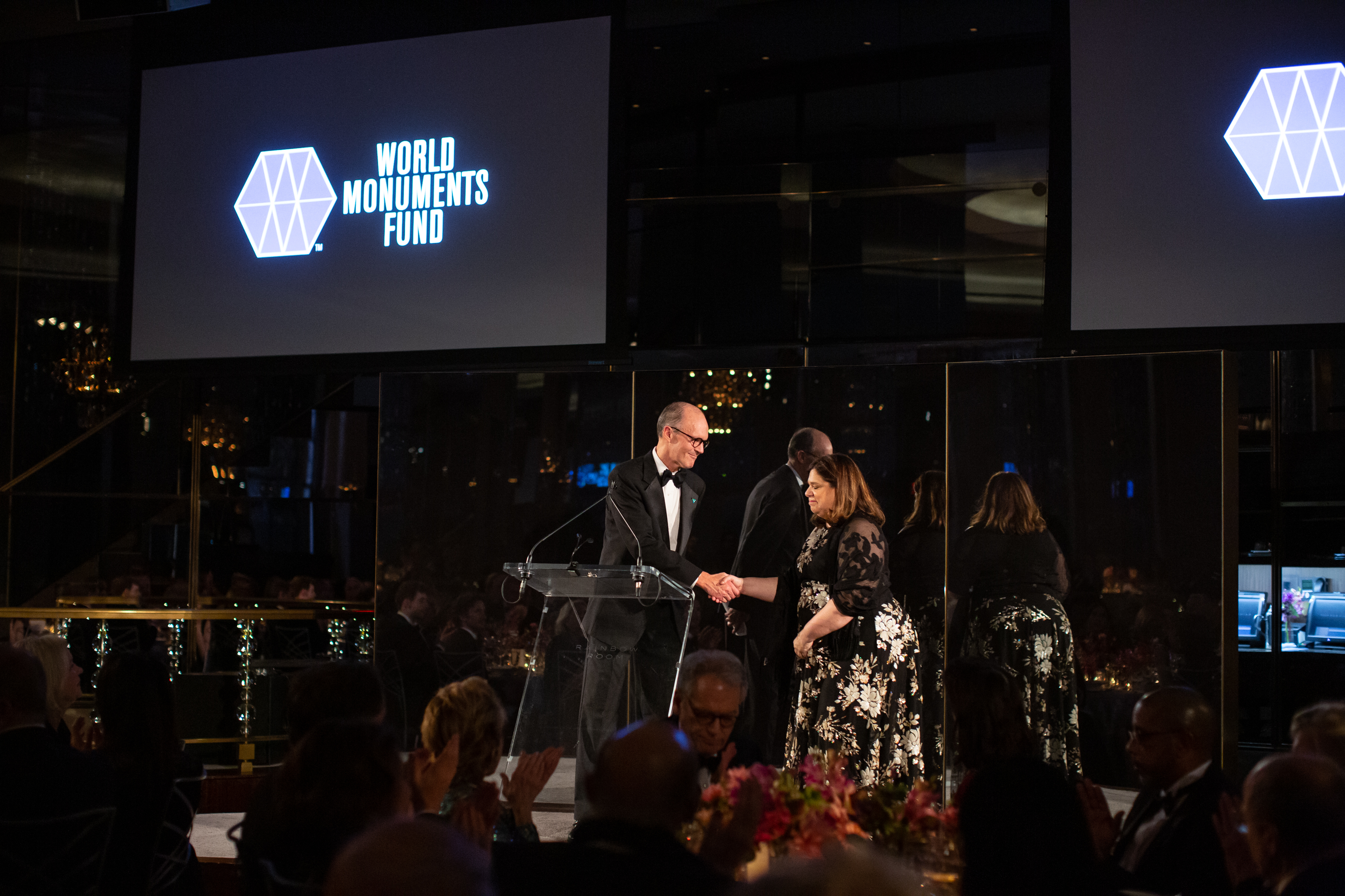 A man shakes a woman's hand on stage at the World Monuments Fund’s 2018 Hadrian Gala