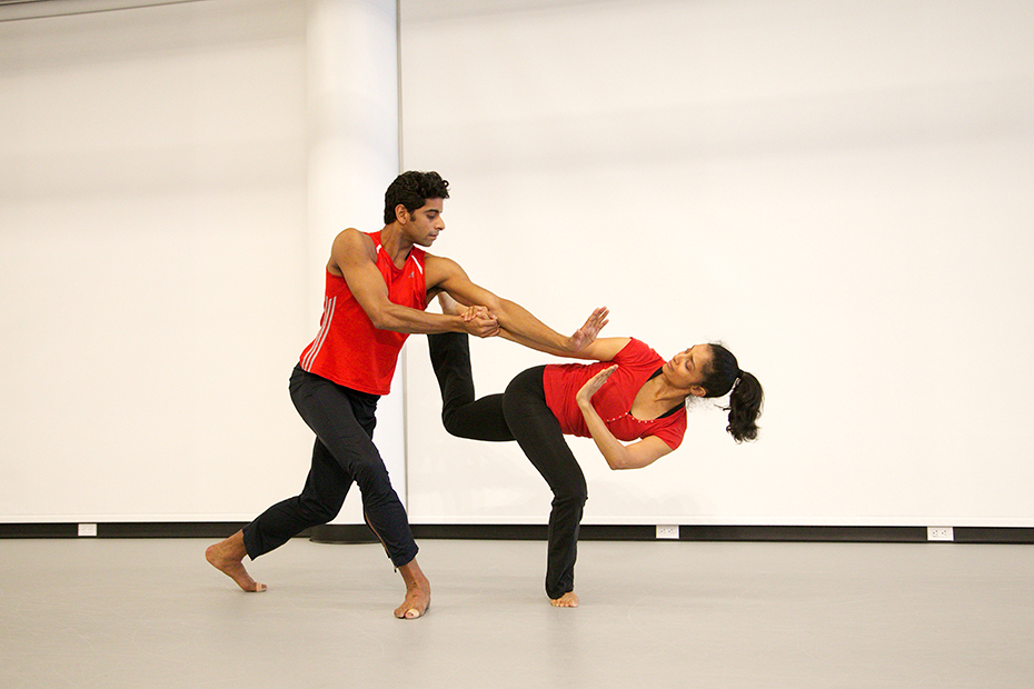 A dancing couple perform a figure in which the woman is supported on one leg which bends and the other leg rests on her partner's shoulder while the man supports her by holding her hand