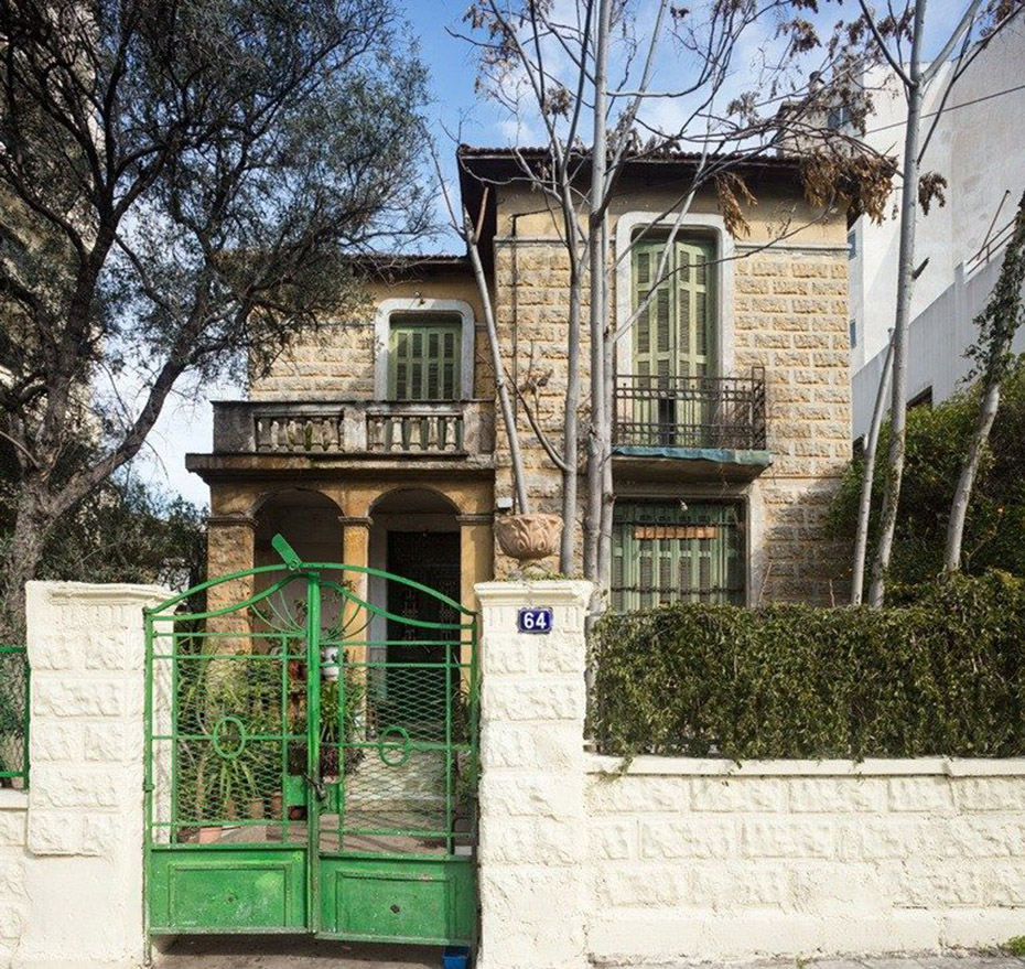 A beige, stone house with green windows and a green front door