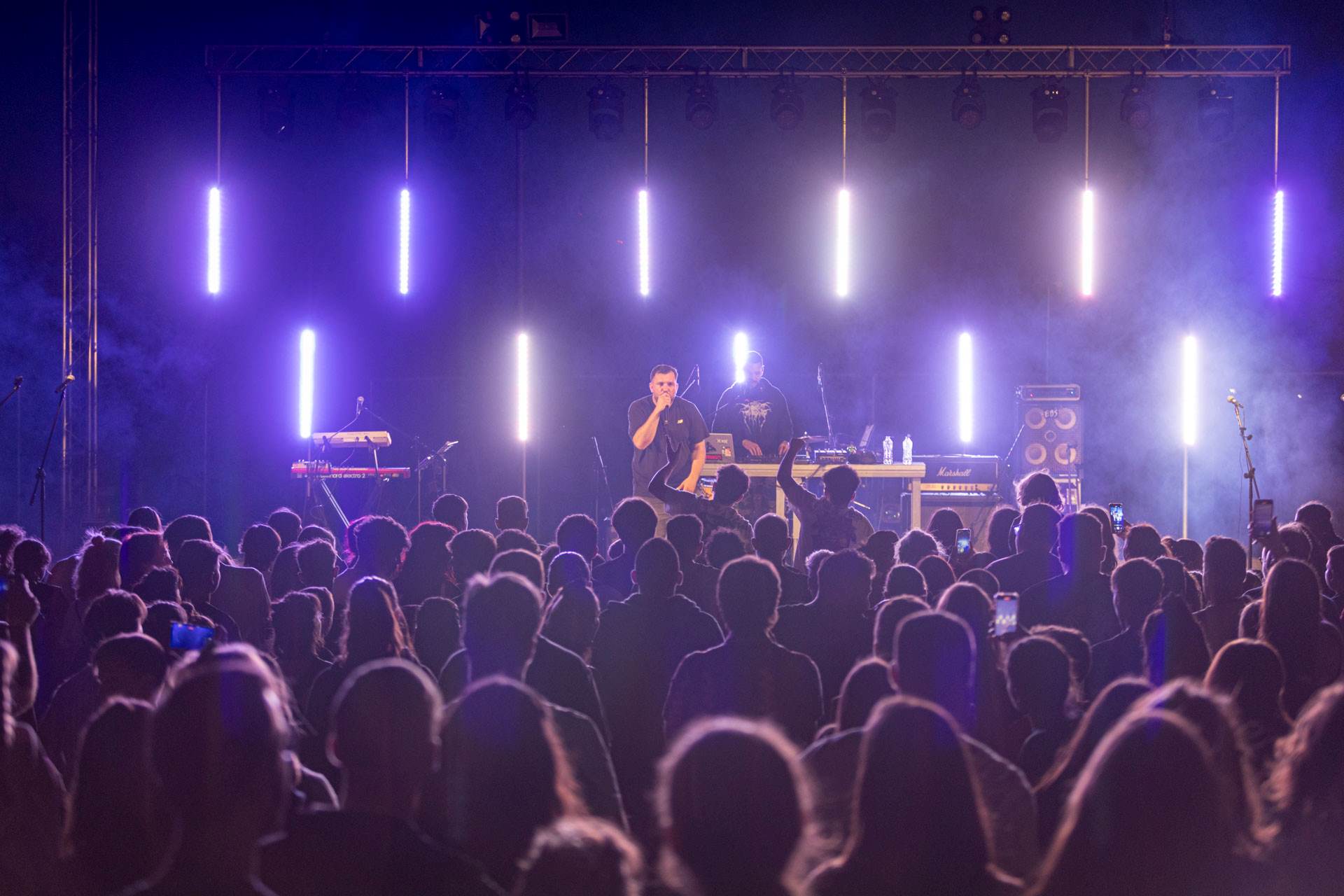 A crowd of people listening to a singer on stage.