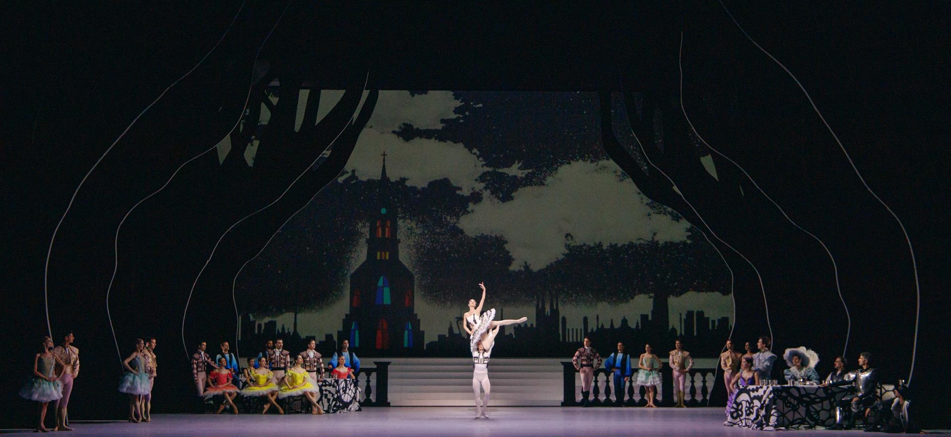 Main ballet dancers at the center of the stages doing a pose while chorus stand still on both sides.