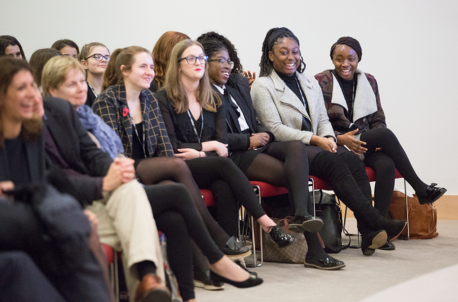 A few women who are part of the audience laugh