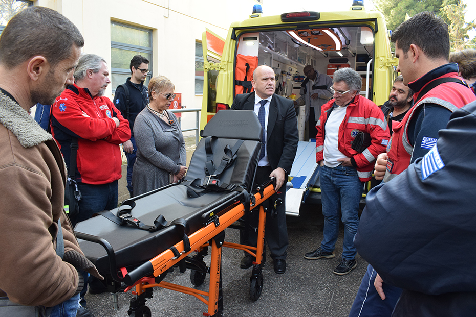 A group of EKAV crew members look at the equipment, specifically a stretcher, of an ambulance