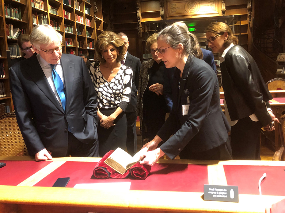 A woman shows members an old book that is part of a collection in the library