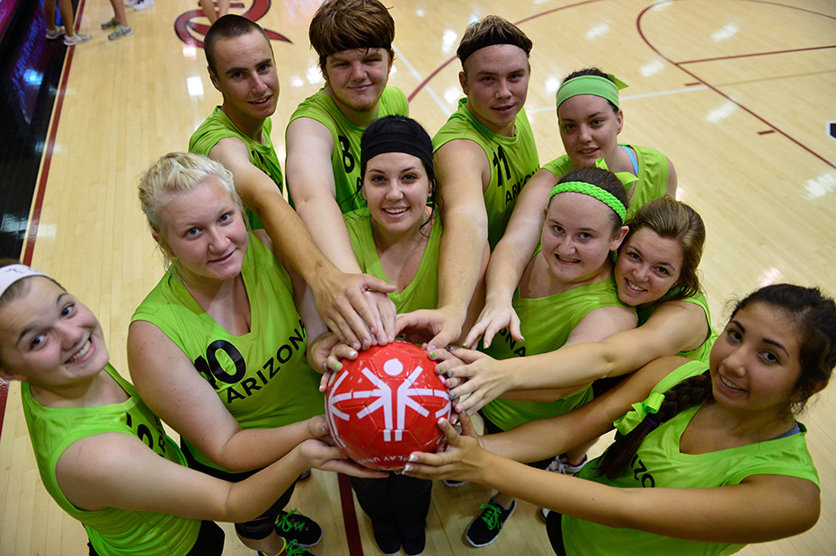 A group of young people all holding a ball together and smiling for a commemorative photo