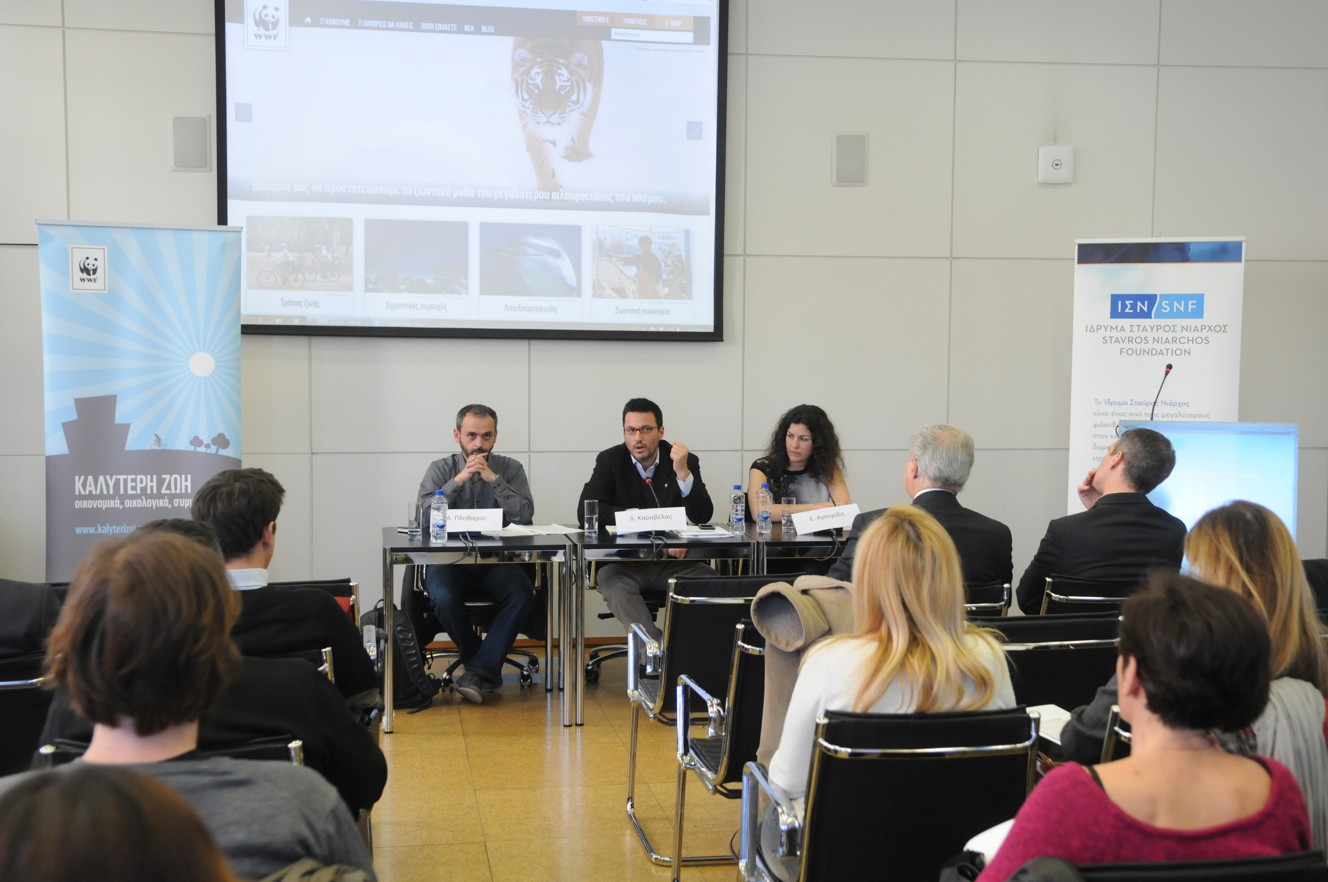 Three people sit in a conference table and give a presentation