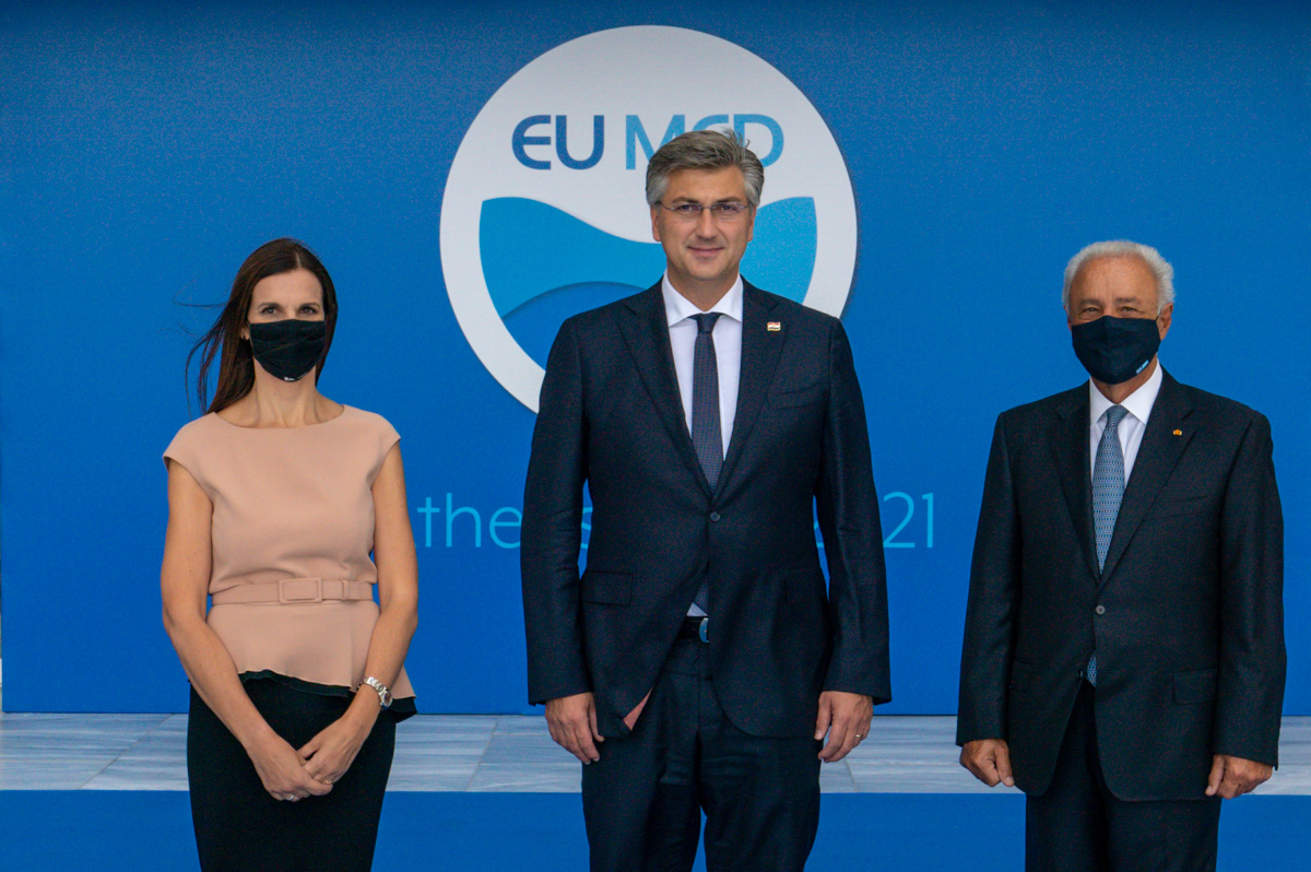 Two men and a woman are photographed in front of the EU MED background