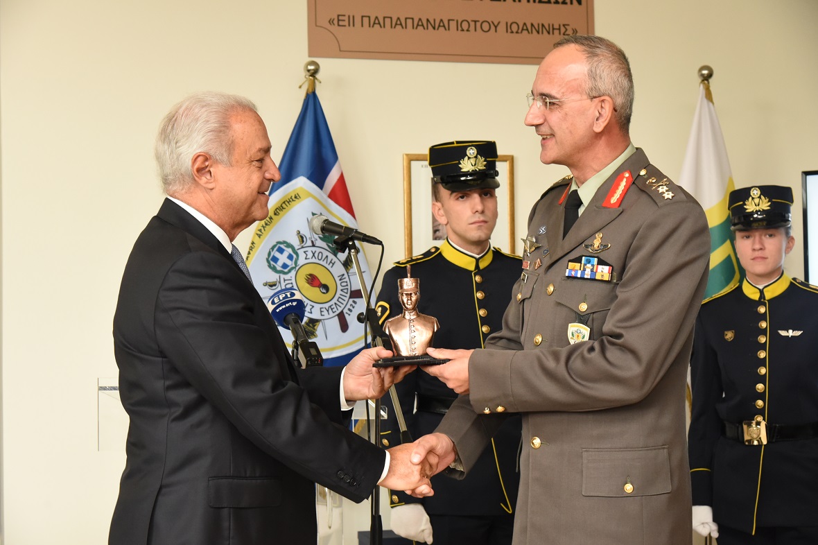 A man receives an award from a man dressed in army attire