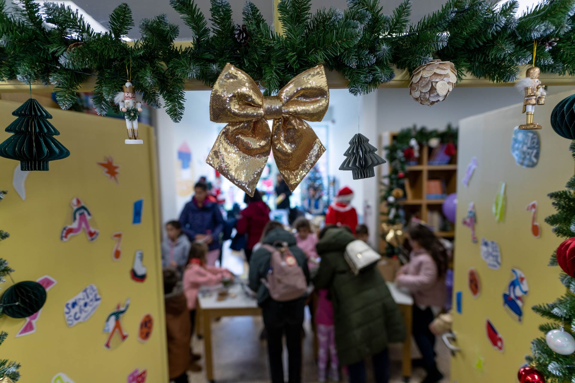 Children surrounding the table inside the doors of Vamvakou Santa School, surrounded by stickers and decorations.