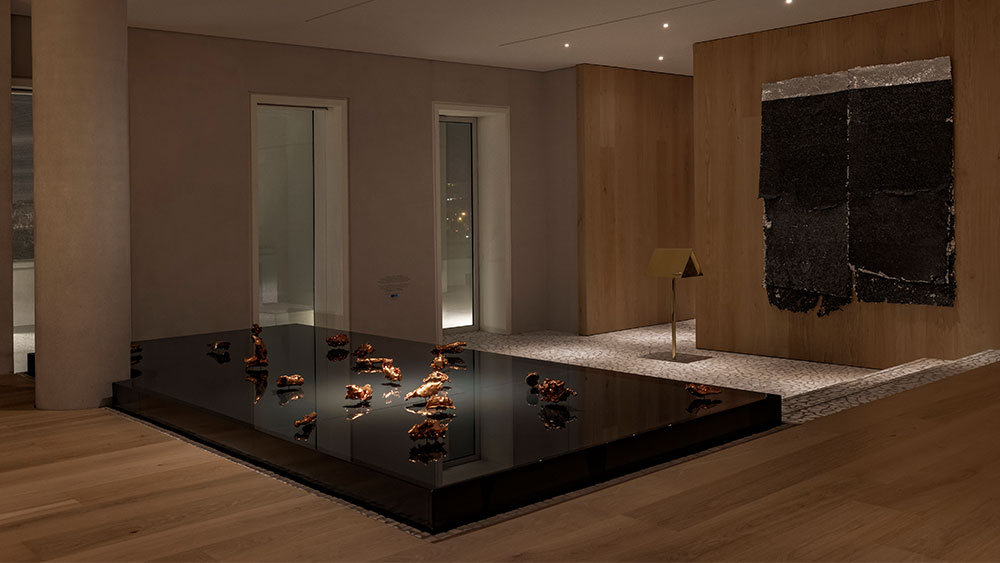 In an interior space, there is a staircase like a stage on which there are small works of art