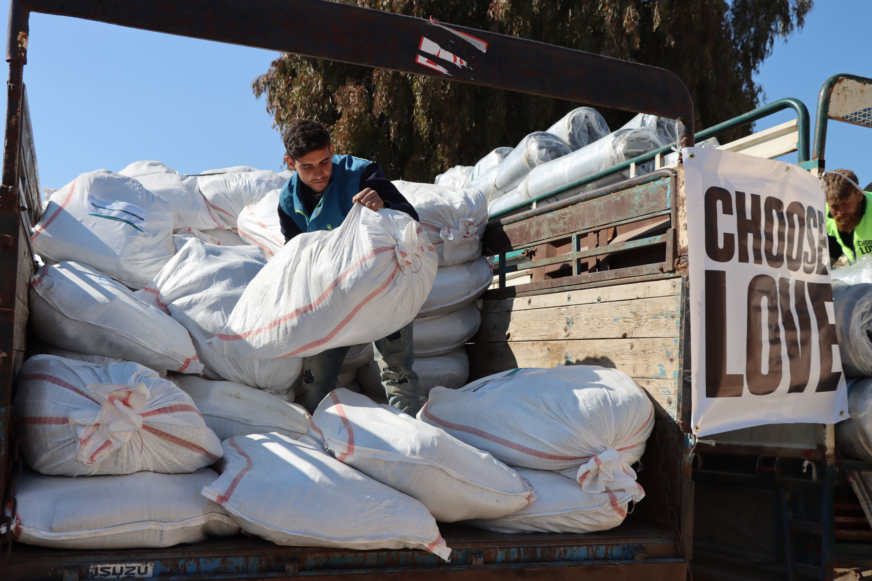 A person unloads white sacks from a truck labeled