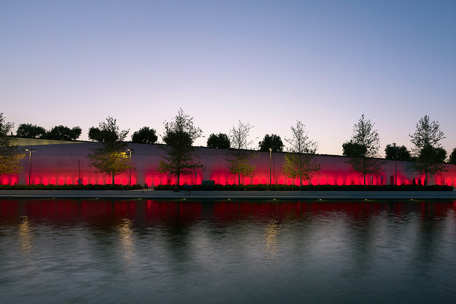 Photo showing a pond at the end of which there is an illuminated wall