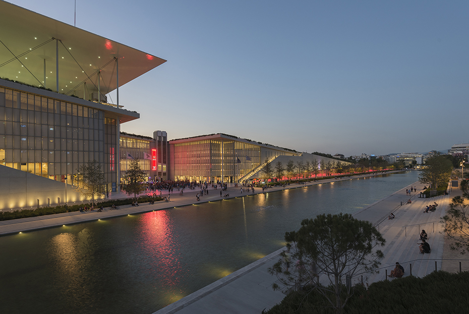 Photo showing a lake and a large glass building parallel to it