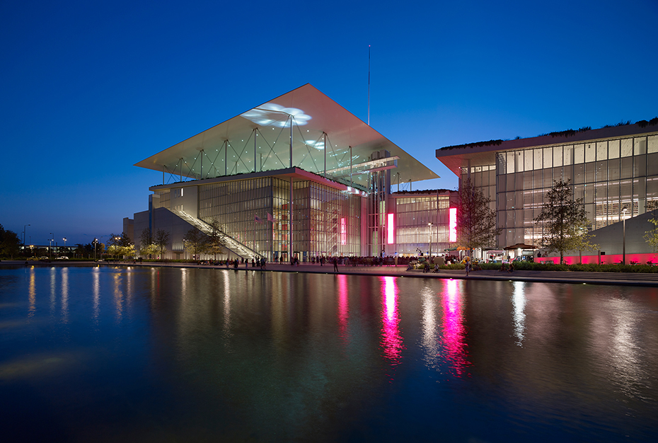 Photo showing a pond behind which there is a large glass building
