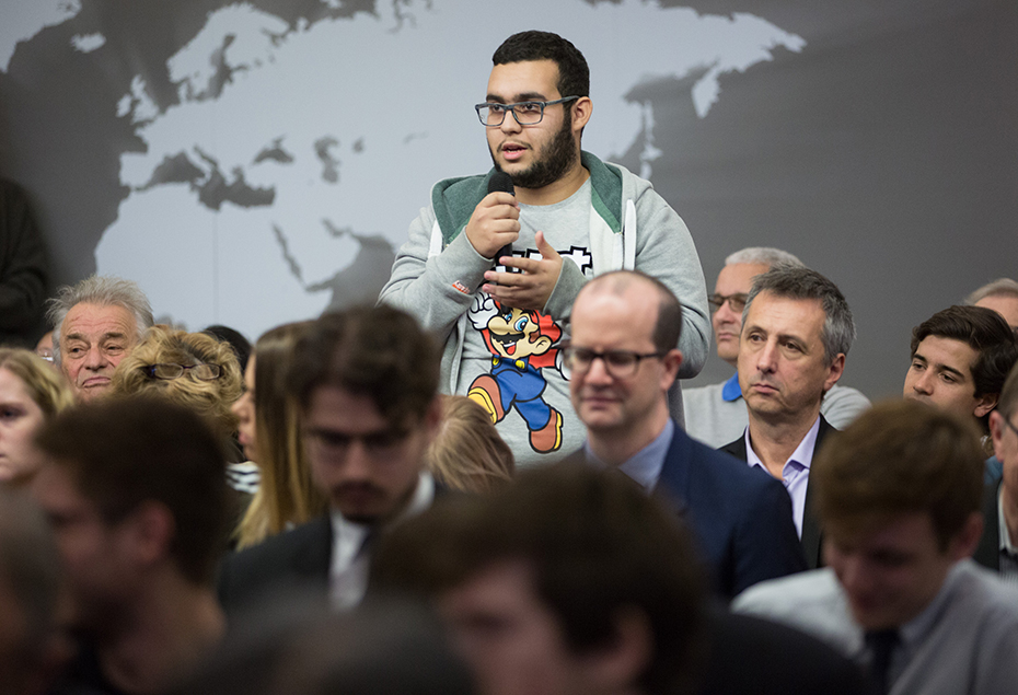 A young man in the audience stands to ask a question