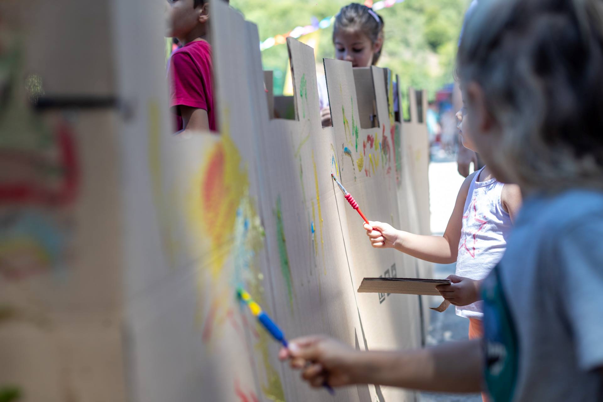 Children holding paintbrushes and painting on canvases.