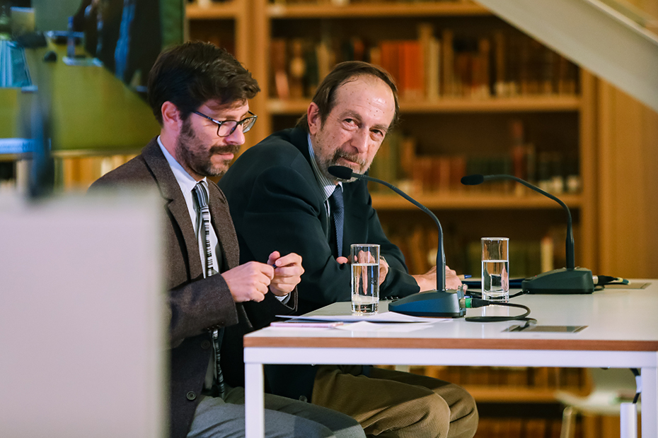 Close-up photo of two men sitting on the stage