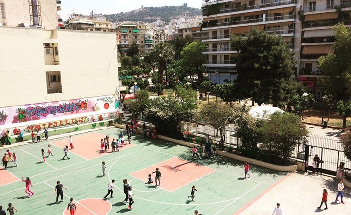 Photo taken from above showing the basketball courts of a school full of children playing