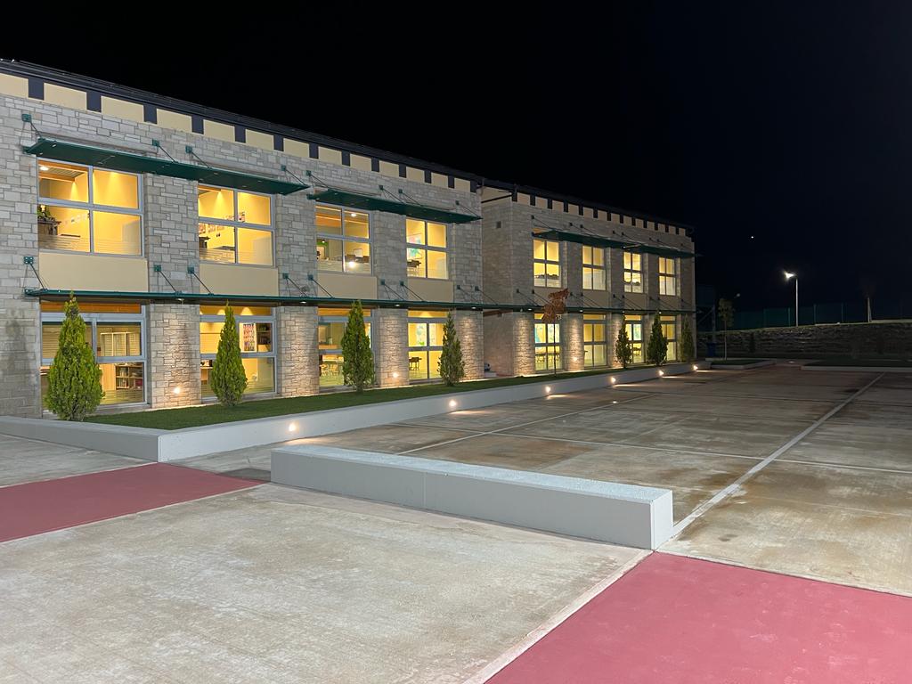 Exterior view of the school at night with the interior of the building illuminated