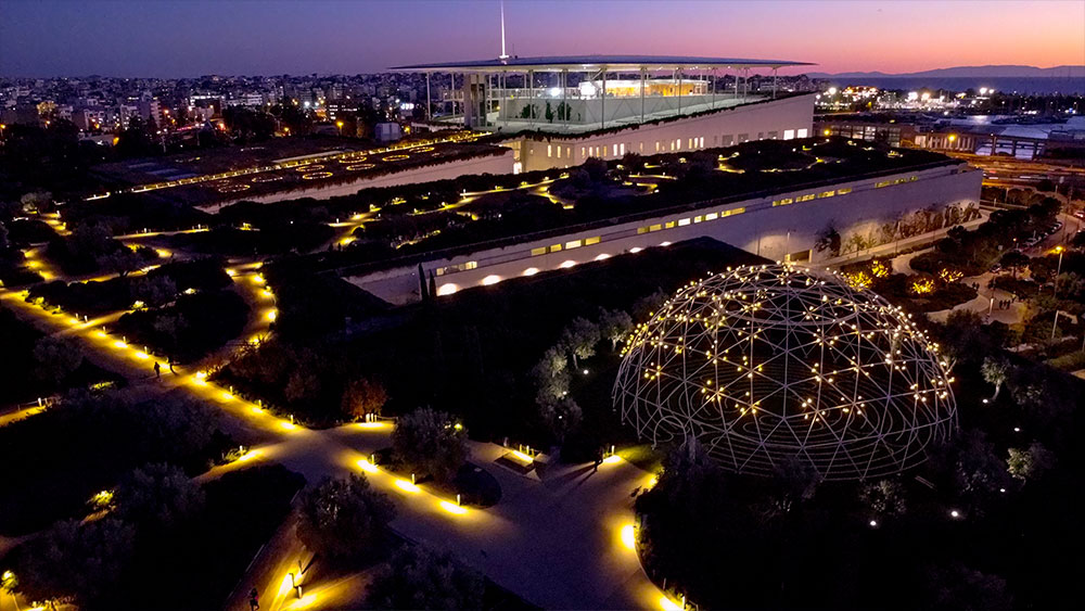 A distant photograph that conveys a lit up Stavros Niarchos Foundation Cultural Center