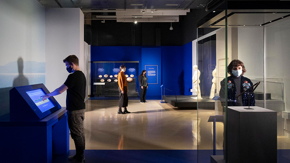 Four people scattered around the museum with ancient Greek exhibits