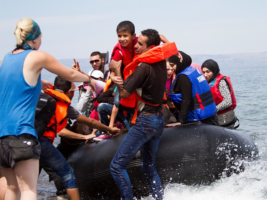 Many refugees in life jackets are rescued from a lifeboat