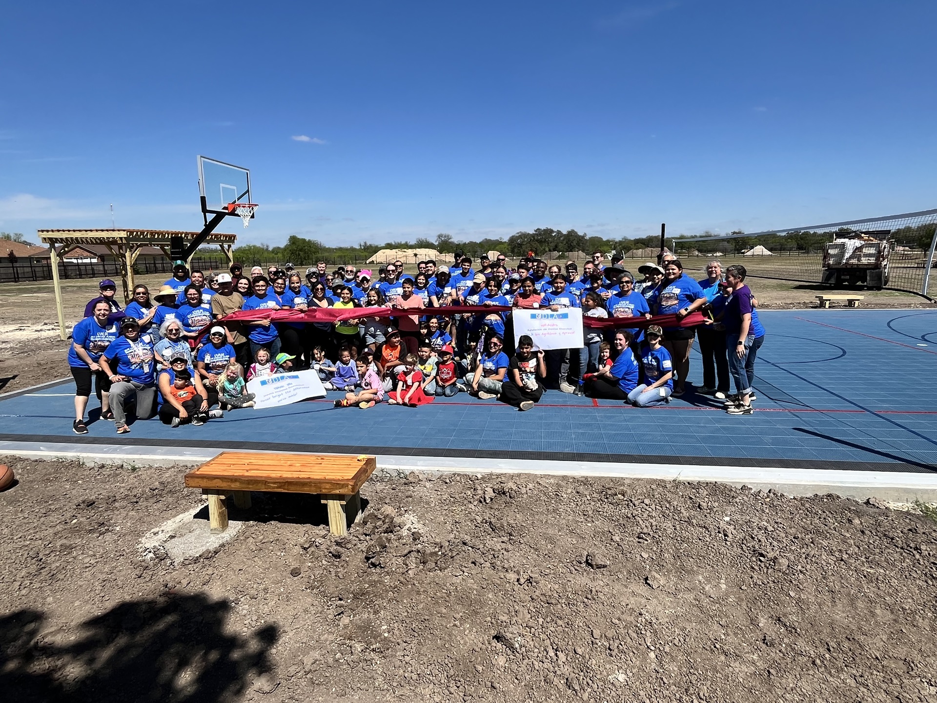 Group of people in blue shirts posing for a photo on a basketball court.