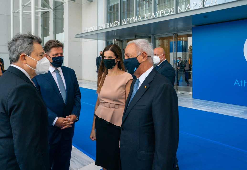 Three men and a woman talking to each other in front of the entrance of the Stavros Niarchos Foundation Cultural Center