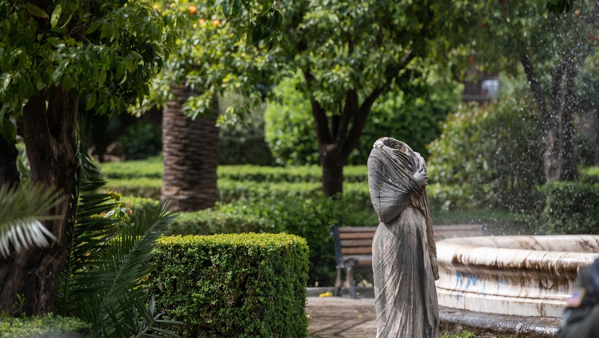Photo showing a statue of a headless female figure standing in the middle of a green park