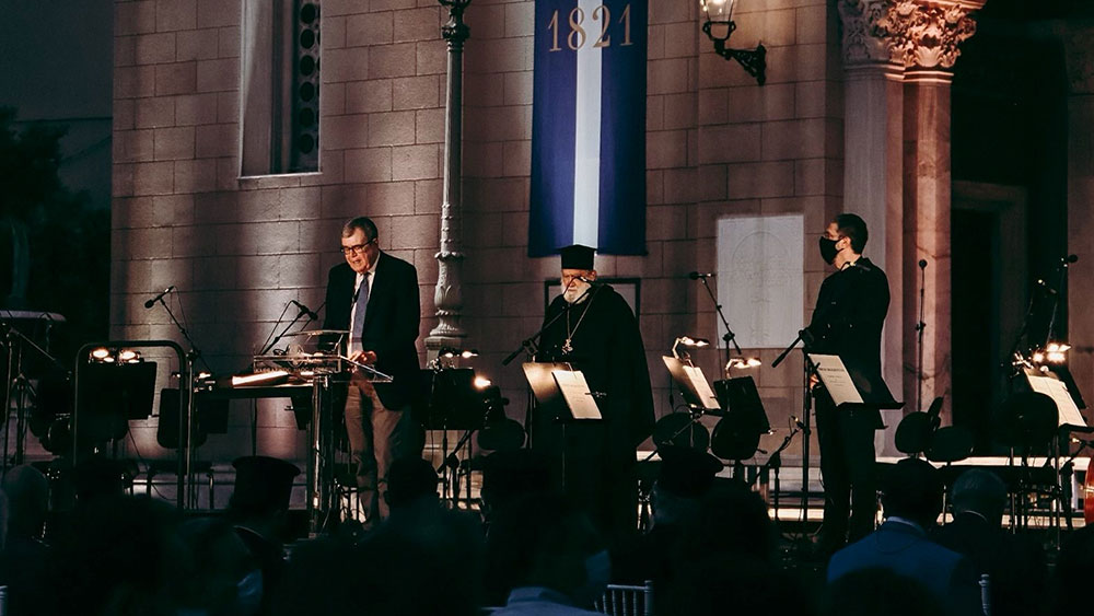 In one scene there are three men, one is talking on the podium, the second is a priest and is standing while the third is watching them.