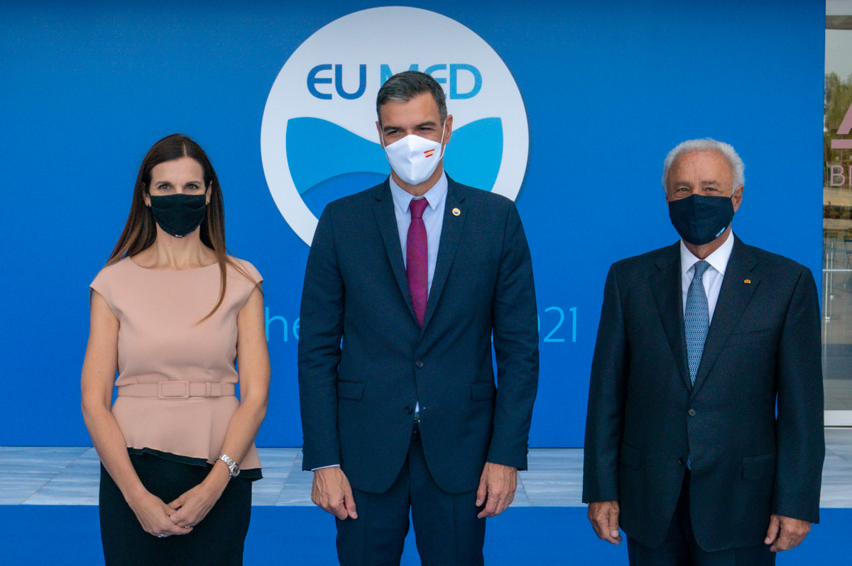 Two men and a woman photographed in front of the EU MED background