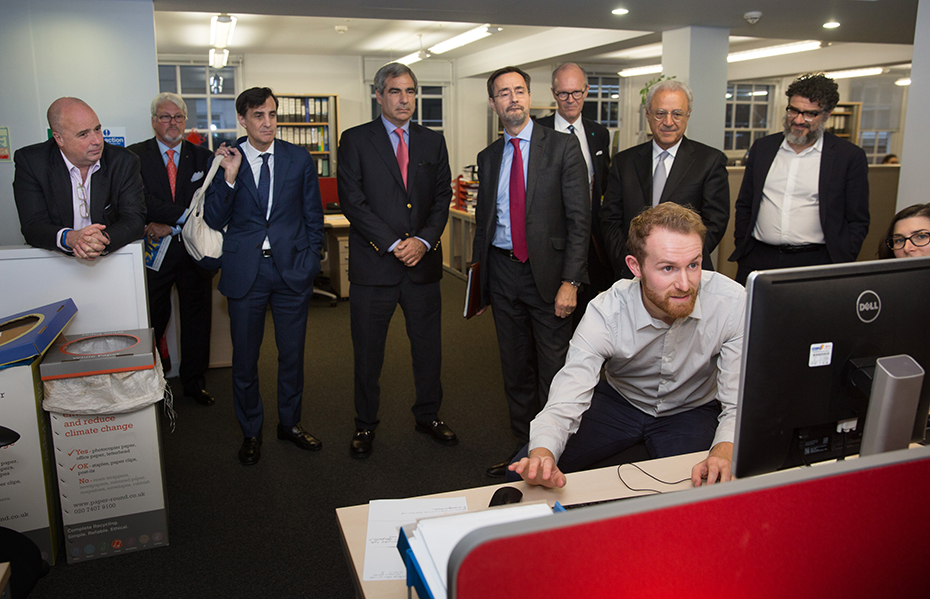Andreas Dracopoulos, co-president of the Stavros Niarchos Foundation, looks at a computer screen attentively with other people at Chatham House