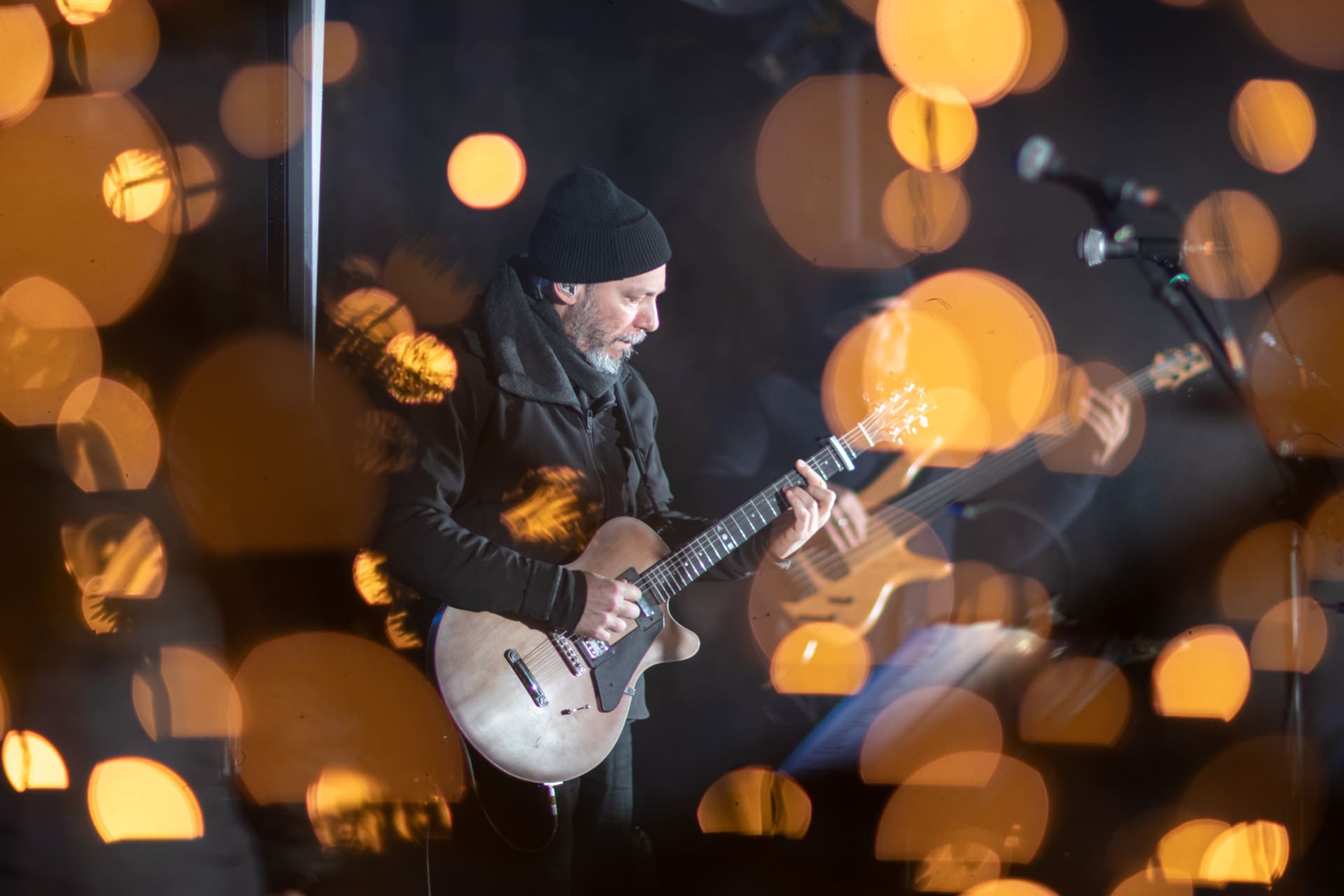 Alkinoos Ioannidis plays the quitar on a stage surrounded by Christmas lights.
