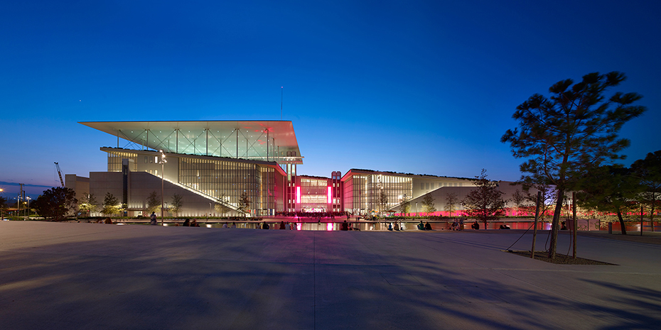 The exterior of a large glass building illuminated at night