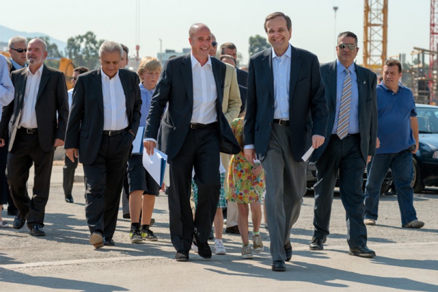 Andreas Dracopoulos, co-president of the Stavros Niarchos Foundation, and Antonis Samaras, the Prime Minister of the Hellenic Republic, walk with a group of people and smile