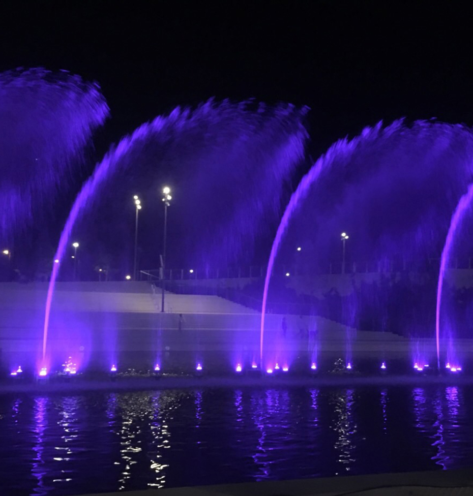 A fountain in the middle of a lake throws its water very high and makes patterns in the air