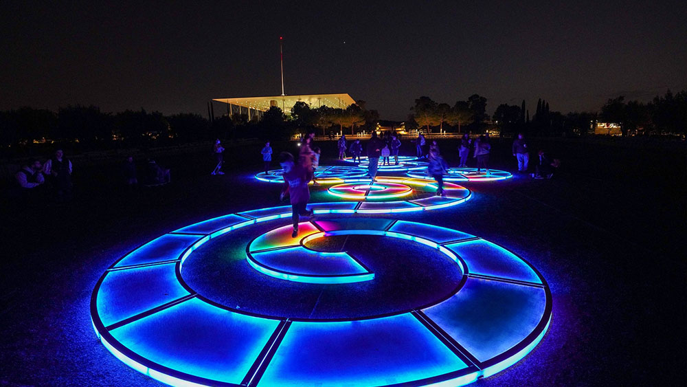 Children play on a lit-up maze-like game on the ground at the Stavros Niarchos Foundation Cultural Center