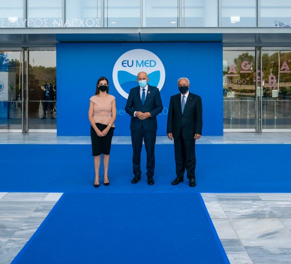 Two men and a woman are photographed in front of the EU MED background