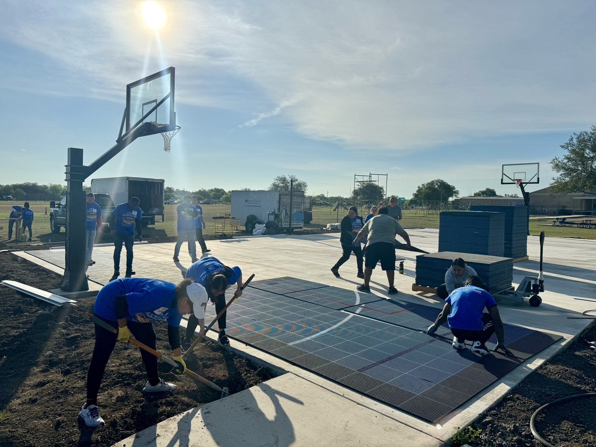 People in blue shirts conduct renovation works on a basketball court