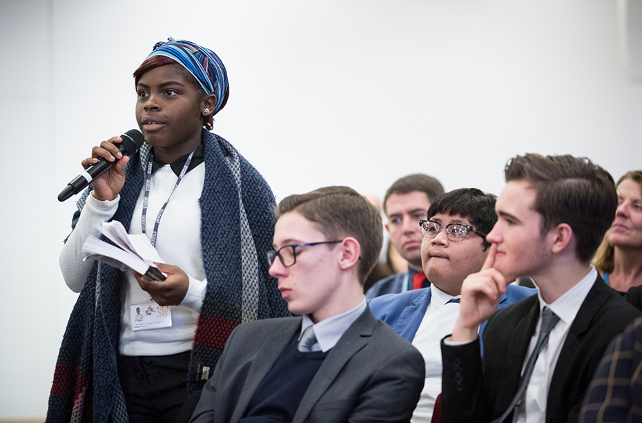 A young woman in the audience stands to ask a question