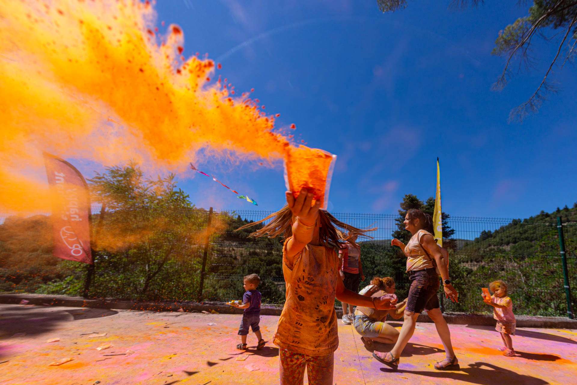 Kid holding a bag full of color and throws it in the wind.