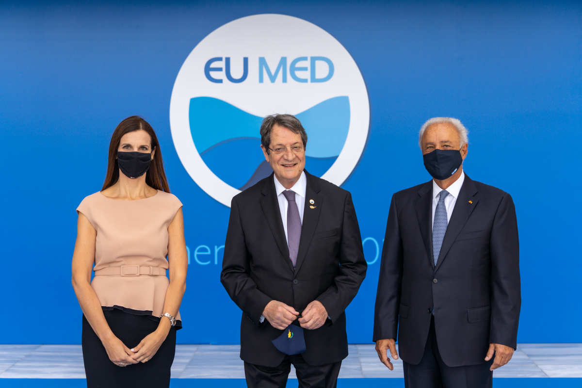 Two men and a woman photographed in front of the EU MED background