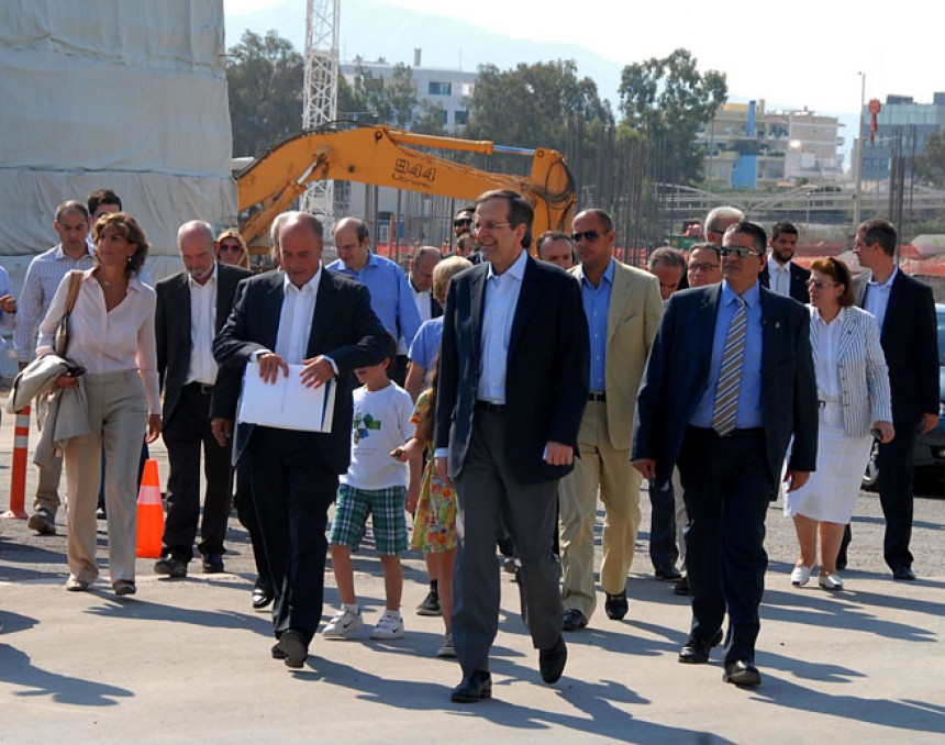 Antonis Samaras, the Prime Minister of the Hellenic Republic, walks next to Andreas Dracopoulos, the co-president of the Stavros Niarchos Foundation, in front of other people and two kids, at the construction site of the Stavros Niarchos Foundation Cultural Center