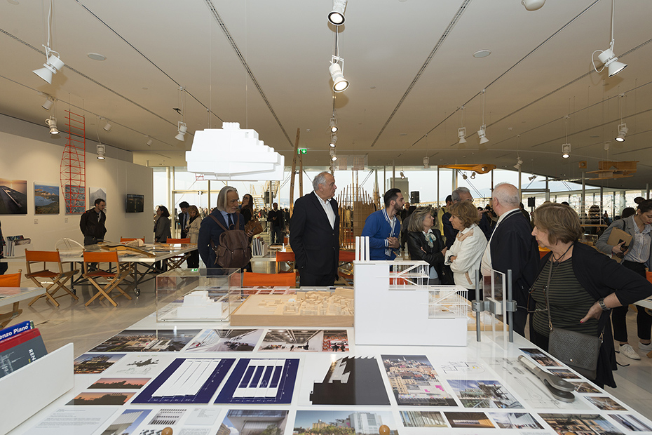 Photo showing people looking at a table full of drawings, memos and models of buildings