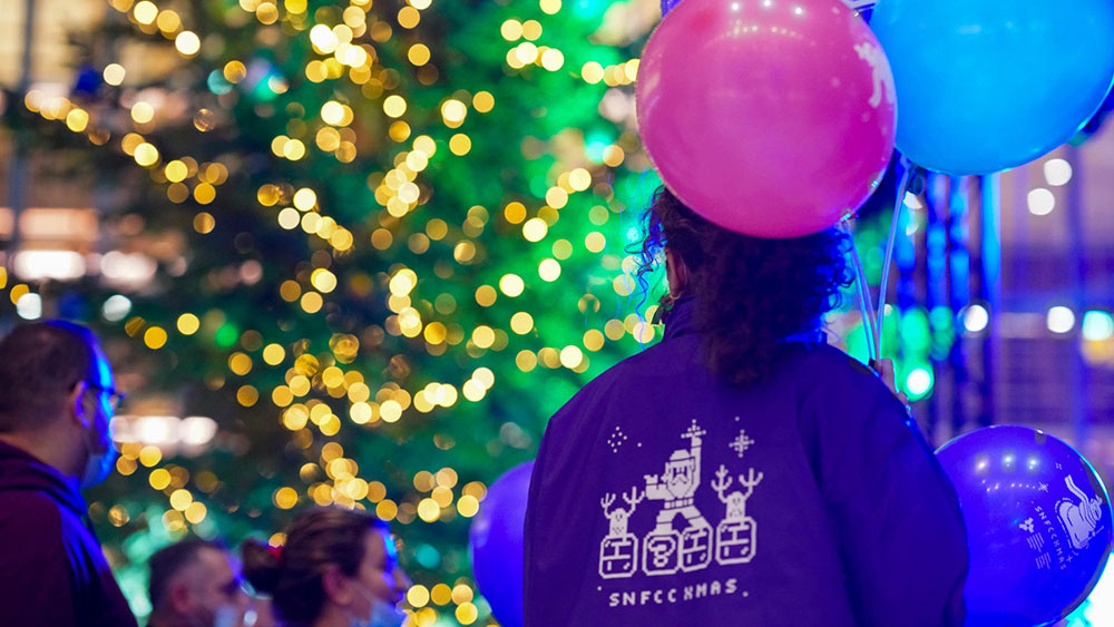 A woman holding balloons looks onto the the decorated trees